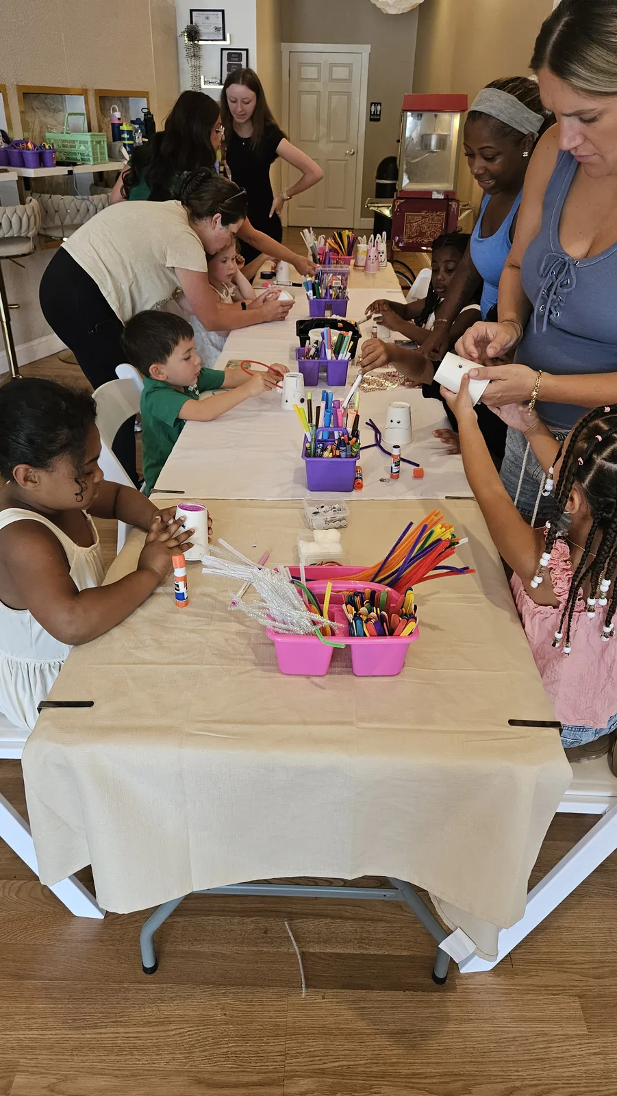 Children and adults making colorful crafts together at a STEAM Sprouts activity table