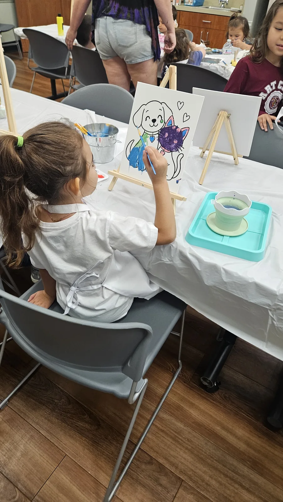 Child painting a colorful canvas at a STEAM Sprouts craft table