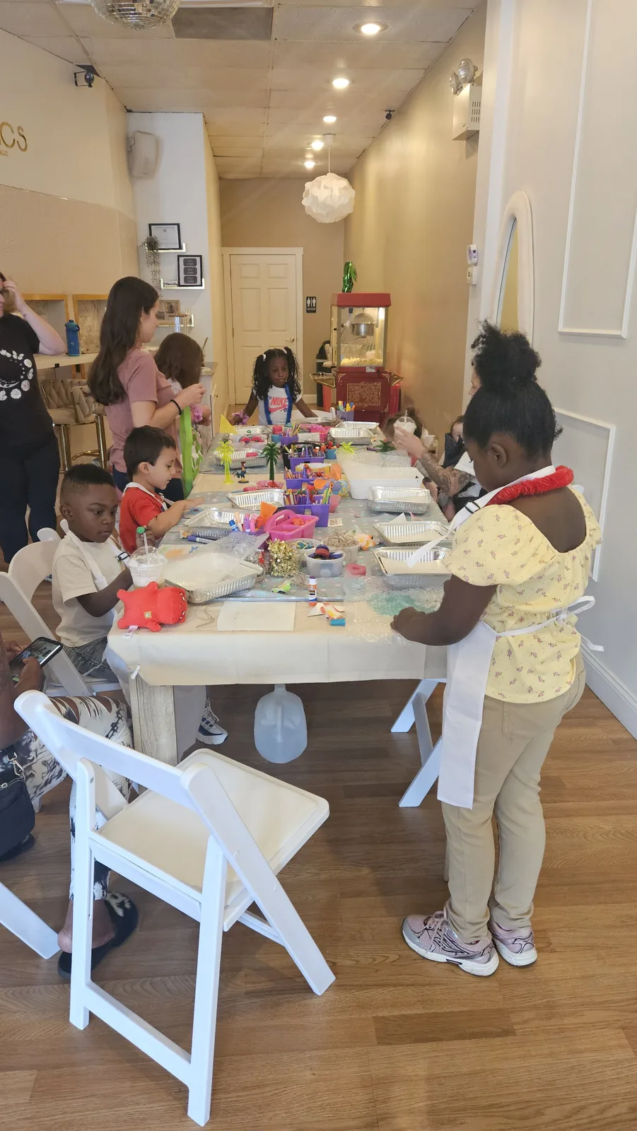 Children and adults seated around a decorated craft table in a community event space
