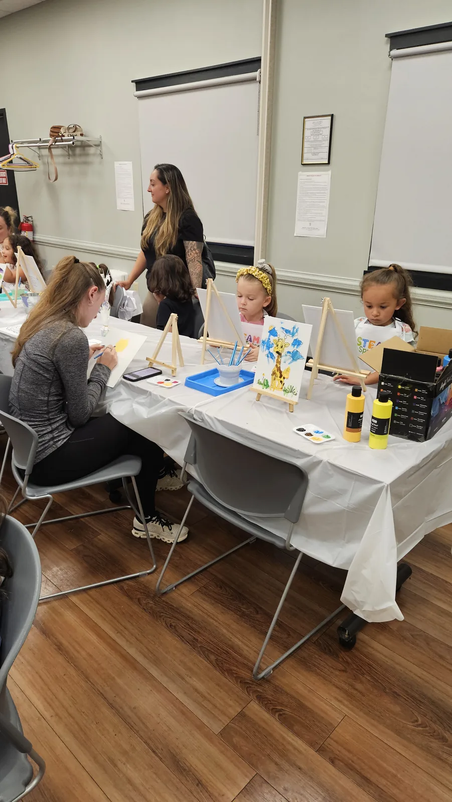 Instructor and children working on projects at a STEAM Sprouts workshop table