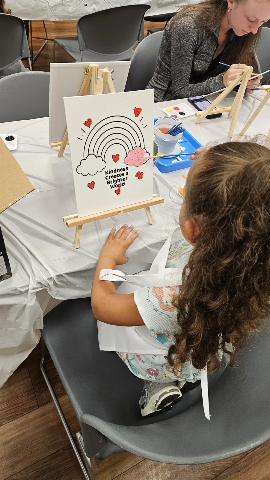Child creating a rainbow and heart artwork during a hands-on STEAM Sprouts activity