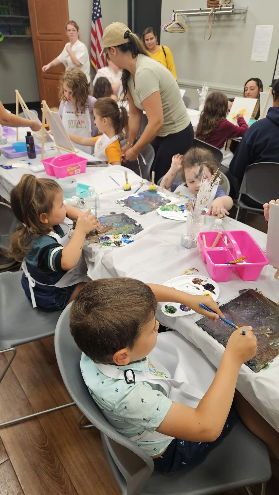 Instructor helping children create colorful projects at a community craft table